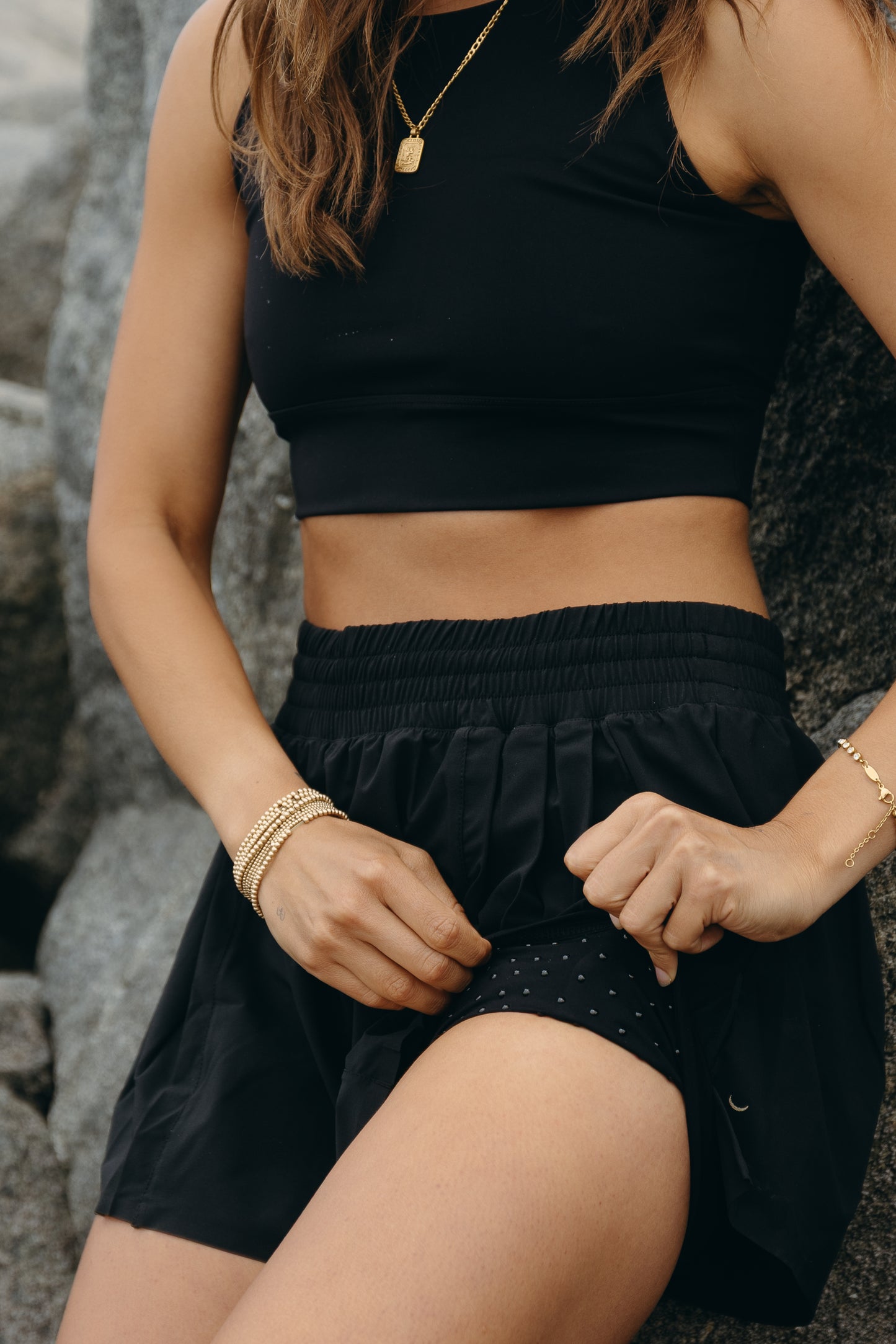 Modèle portant le short L’Original Flowy, doté d’une couche extérieure plissée ultra-légère et d’un short intérieur sculptant à compression ciblée. Zoom sur le short intérieur et les MicroPerle®. Ce design 2-en-1 allie fluidité féminine et maintien performant, avec l’intégration brevetée des MicroPerle® et une poche intérieure discrète pour y glisser l’essentiel — téléphone ou balle de tennis.