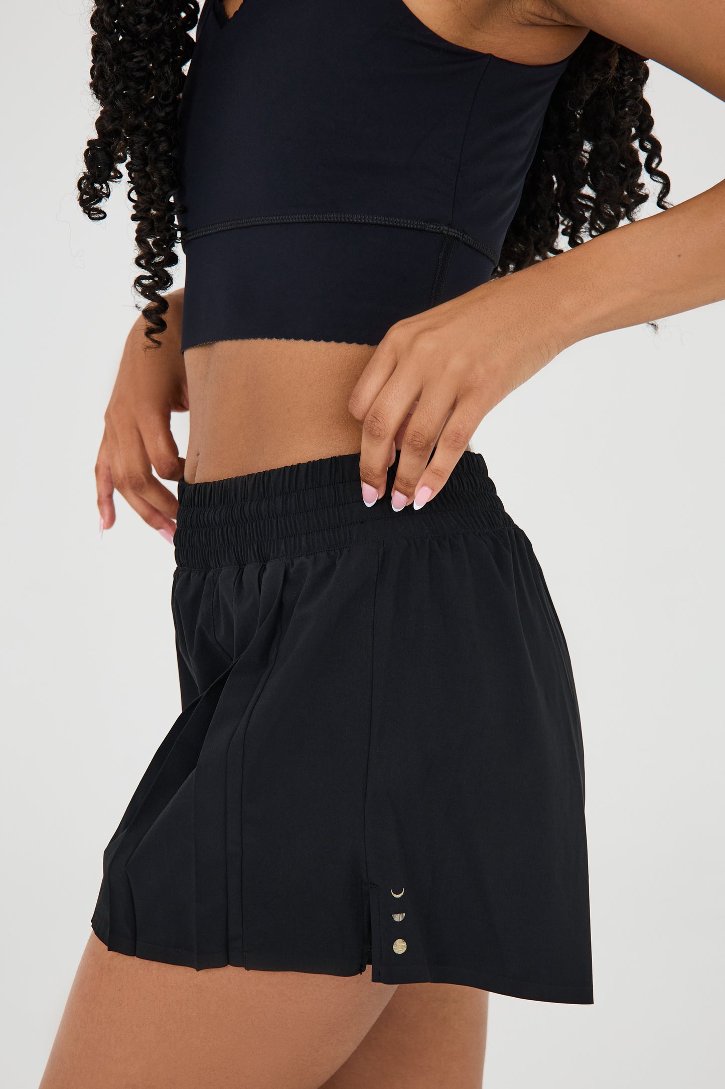 Modèle portant le short L’Original Flowy, composé d’une couche extérieure plissée ultra-légère et d’un short intérieur sculptant à compression. Ce design 2-en-1 allie élégance en mouvement et maintien performant, avec l’intégration brevetée des MicroPerle® et une poche intérieure discrète pour l’essentiel — téléphone ou balle de tennis.