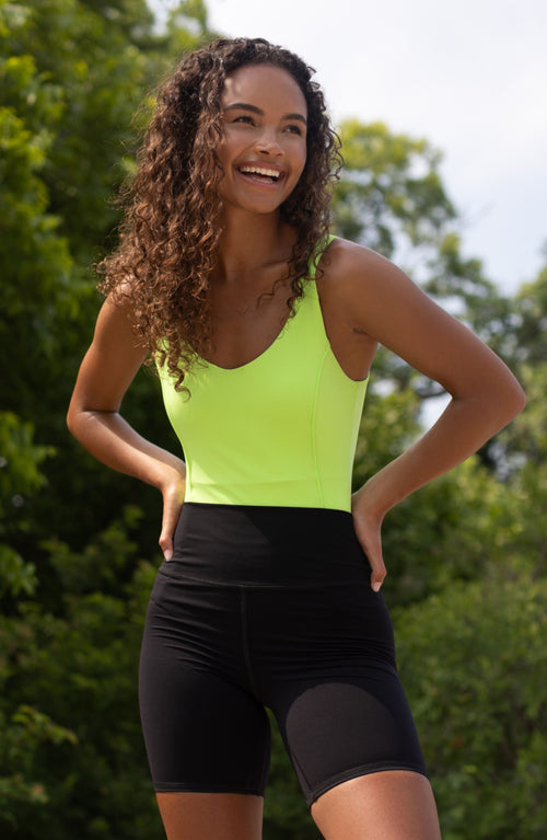 Charger l&#39;image 1 dans la galerie. Mannequin portant le Riviera Bodysuit couleur citron vert, un élégant maillot de bain et body deux-en-un confectionné dans un tissu de compression certifié OEKO-TEX® et doté de la technologie brevetée MicroPerle®. Conçu pour lisser, sculpter et soutenir le corps, il favorise le drainage lymphatique et la circulation, tout en offrant une élégance sans effort, de la piscine au dîner. Une pièce alliant luxe épuré et bien-être.