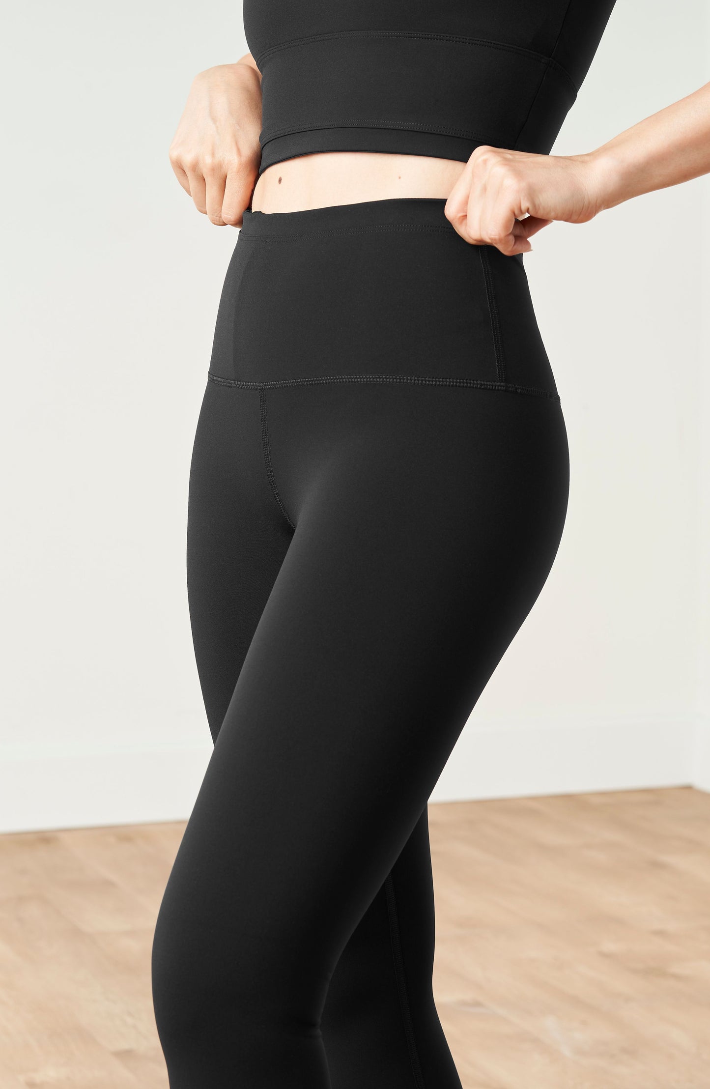 Mannequin portant le legging et brassière Lisse en couleur noire, confectionnés dans un tissu de compression certifié OEKO-TEX®, conçu pour sculpter la silhouette, stimuler la circulation et offrir une sensation lisse et seconde peau.