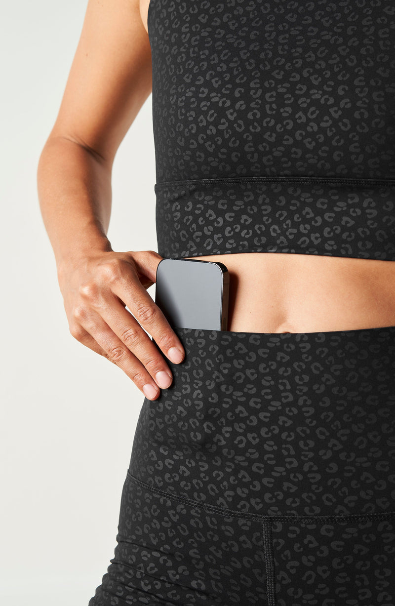 Modèle portant le legging Fierce en noir avec imprimé léopard, conçu avec un tissu compressif certifié OEKO-TEX et notre technologie MicroPerle® pour stimuler le drainage lymphatique, améliorer la circulation, réduire la fatigue et lisser la peau. Legging de compression