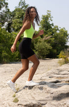 Mannequin portant le short de cyclisme Lisse assorti à son soutien-gorge noir, confectionné dans un tissu de compression certifié OEKO-TEX®, conçu pour lisser, sculpter et soutenir le corps afin d’offrir un confort et une circulation optimaux.