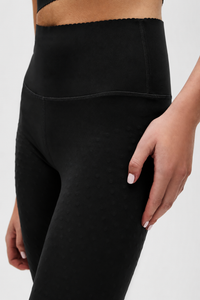 Legging Adorn en noir, avec un élégant bord festonné, en tissu de compression certifié OEKO-tex, notre technologie MicroPerle® pour le drainage lymphatique, une meilleure circulation, la réduction de la fatigue et une peau plus lisse.