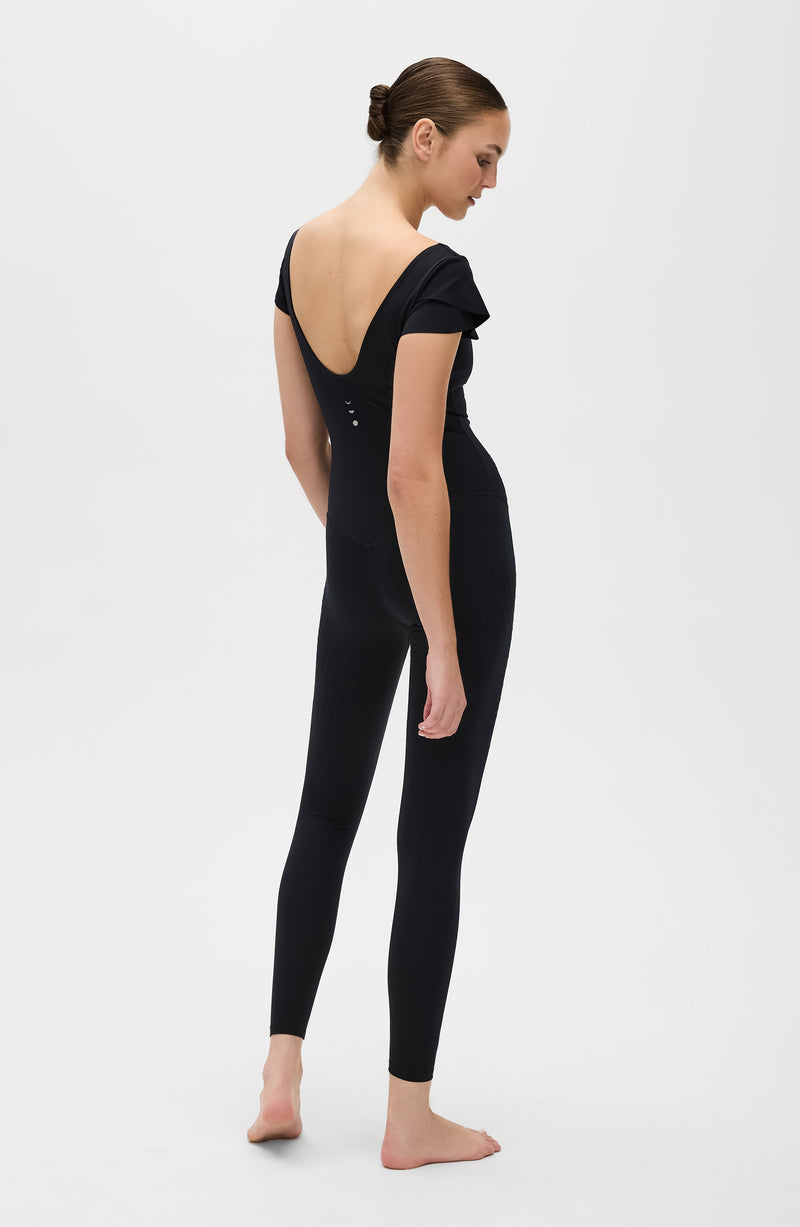 La combinaison Le Cha-Cha, de couleur noire, présente un dos échancré sophistiqué, des manches délicates et une silhouette épurée. Fabriquée avec un tissu de compression certifié OEKO-tex, notre technologie MicroPerle® favorise le drainage lymphatique, améliore la circulation, réduit la fatigue et booste la vitalité.