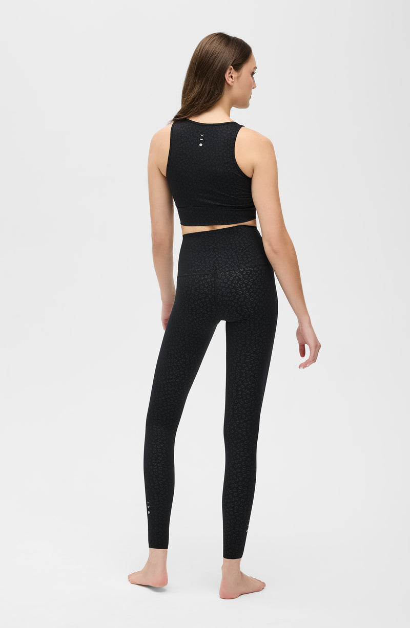 Modèle portant le legging Fierce en noir avec imprimé léopard, conçu avec un tissu compressif certifié OEKO-TEX et notre technologie MicroPerle® pour stimuler le drainage lymphatique, améliorer la circulation, réduire la fatigue et lisser la peau. Legging de compression