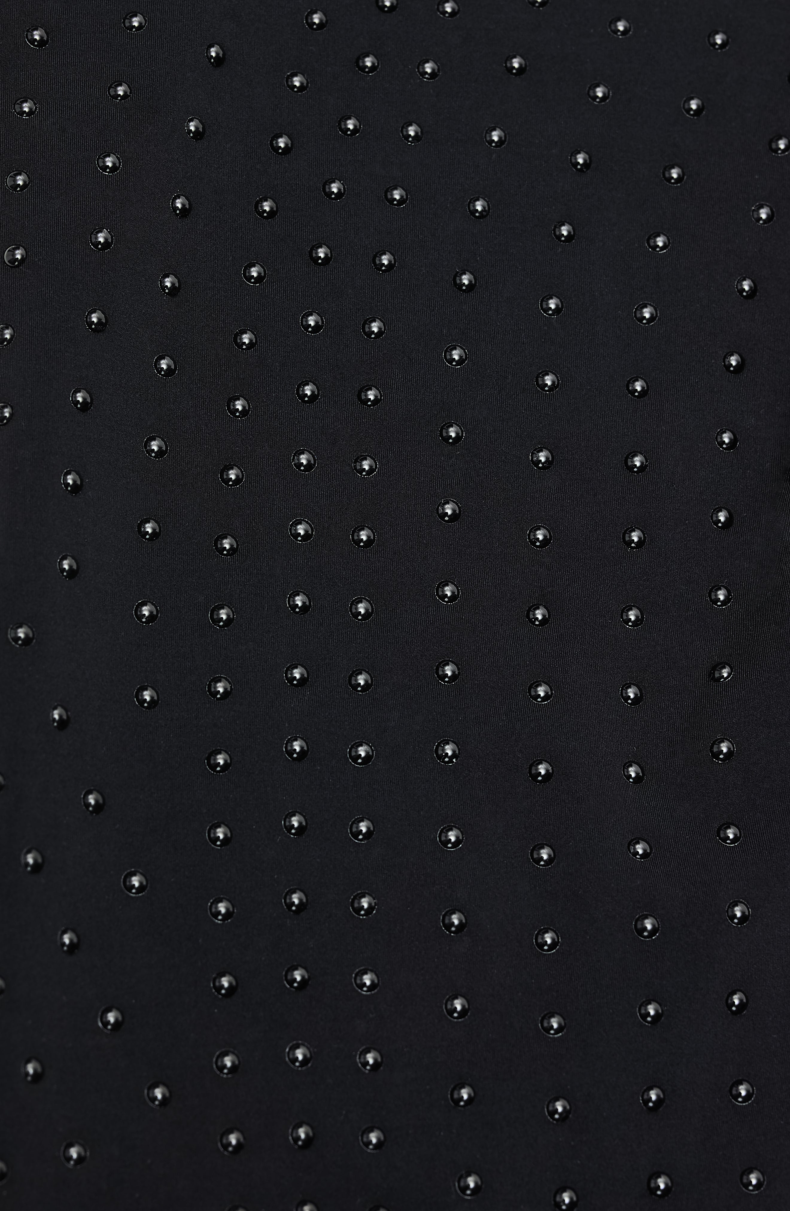 Focus sur les MicroPerle® sur du tissu noir permettant l'amélioration de la circulation, les jambes plus légères