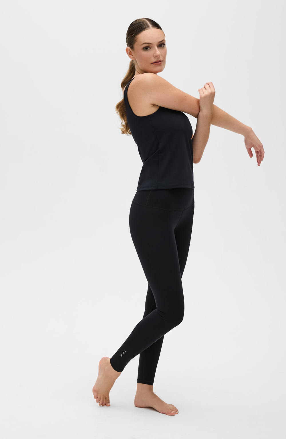 Mannequin portant le legging et débardeur Lisse en couleur noire, confectionnés dans un tissu de compression certifié OEKO-TEX®, conçu pour sculpter la silhouette, stimuler la circulation et offrir une sensation lisse et seconde peau.