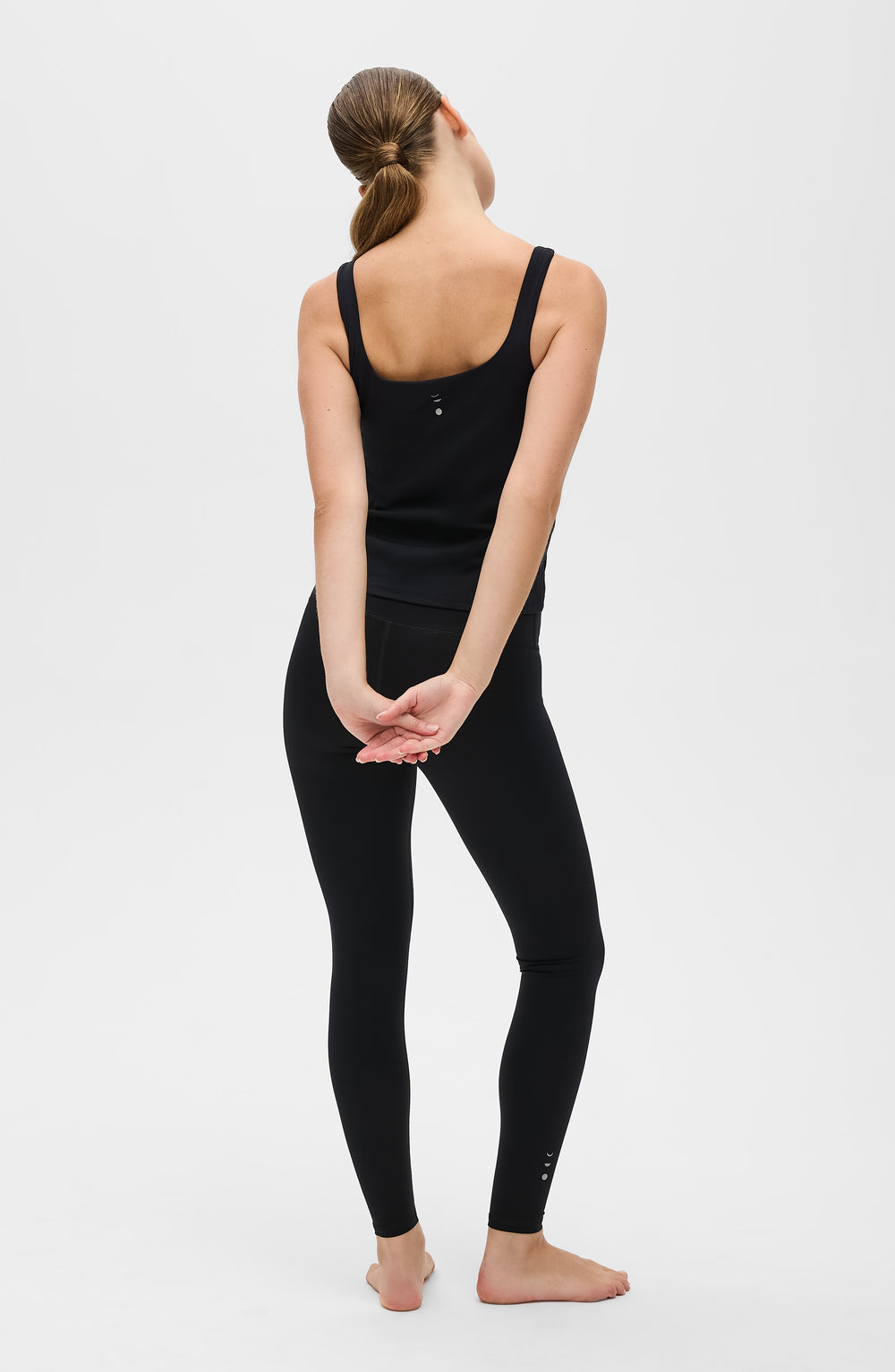 Mannequin portant le legging et débardeur Lisse en couleur noire, confectionnés dans un tissu de compression certifié OEKO-TEX®, conçu pour sculpter la silhouette, stimuler la circulation et offrir une sensation lisse et seconde peau.
