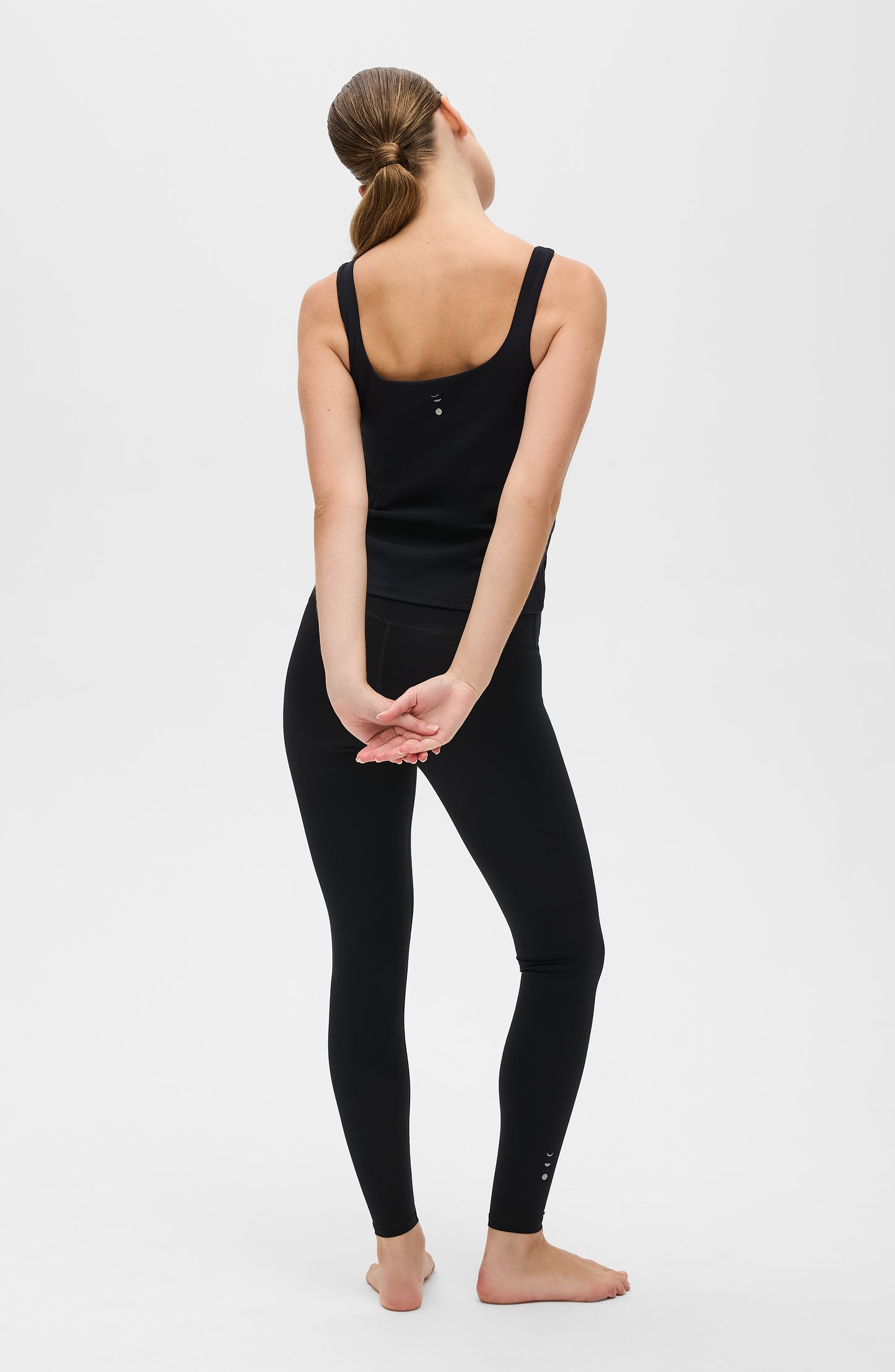 Mannequin portant le legging et débardeur Lisse en couleur noire, confectionnés dans un tissu de compression certifié OEKO-TEX®, conçu pour sculpter la silhouette, stimuler la circulation et offrir une sensation lisse et seconde peau.