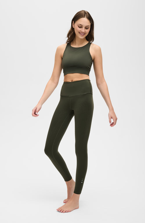 Charger l&#39;image 1 dans la galerie. Mannequin portant le legging L'Original en couleur vert olive, avec tissu de compression certifié OEKO-TEX pour un drainage lymphatique optimal, amélioration de la circulation, réduction de la rétention d'eau