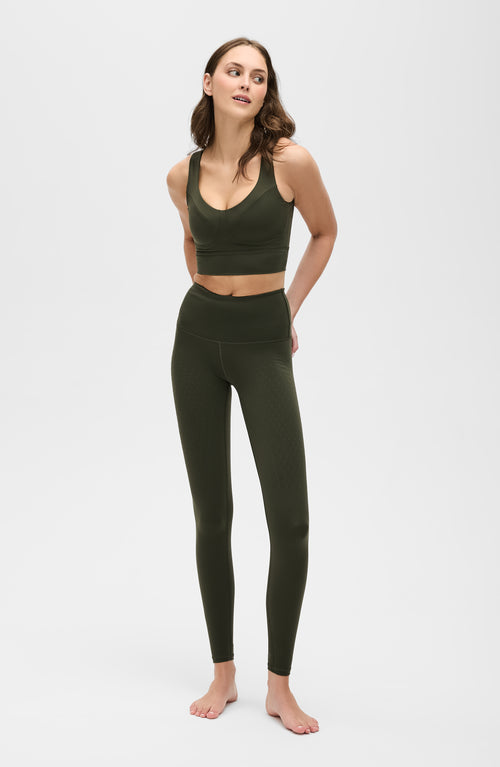 Charger l&#39;image 1 dans la galerie. Mannequin portant le legging L'Original en couleur vert olive, avec tissu de compression certifié OEKO-TEX pour un drainage lymphatique optimal, amélioration de la circulation, réduction de la rétention d'eau