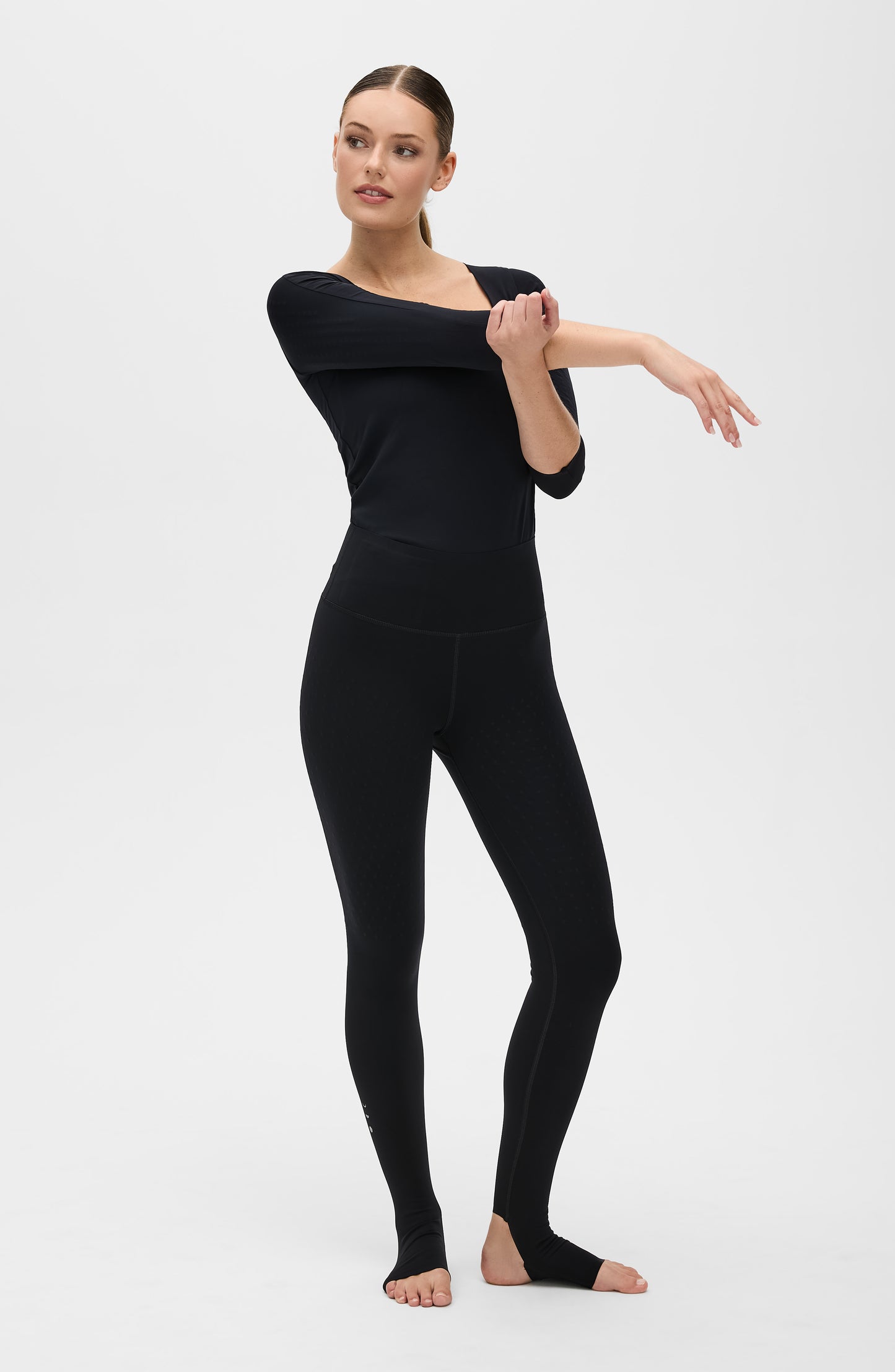 Mannequin portant le legging Fuseau L’Original en noir, accompagné du débardeur Iconic MicroPerle, tous deux confectionnés dans un tissu de compression certifié OEKO-TEX® et dotés de la technologie MicroPerle® d’Elastique, conçue pour stimuler la circulation, favoriser le drainage lymphatique et soulager les douleurs.