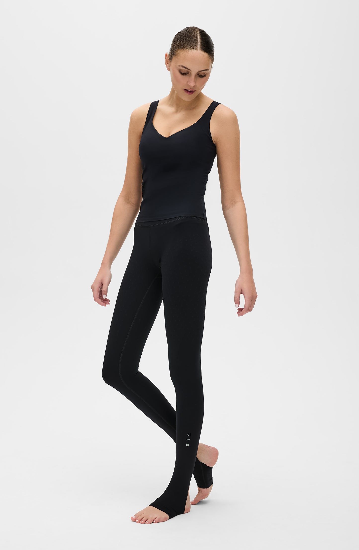 Mannequin portant le legging Fuseau L’Original en noir, accompagné du débardeur Iconic MicroPerle, tous deux confectionnés dans un tissu de compression certifié OEKO-TEX® et dotés de la technologie MicroPerle® d’Elastique, conçue pour stimuler la circulation, favoriser le drainage lymphatique et soulager les douleurs.